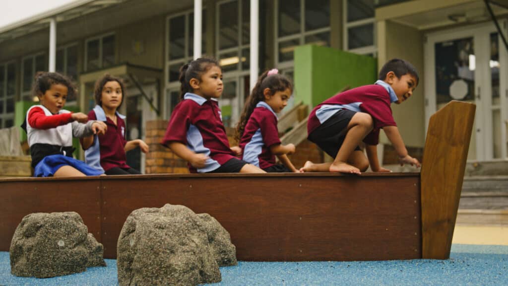 Children in a playground, playing on a boat.